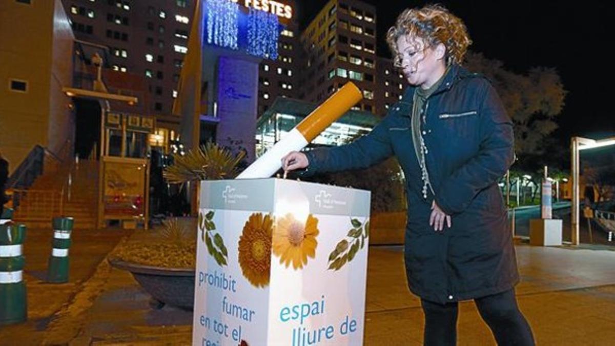 Una mujer apaga una colilla en el gran cenicero de la entrada del Hospital del Vall d'Hebron.