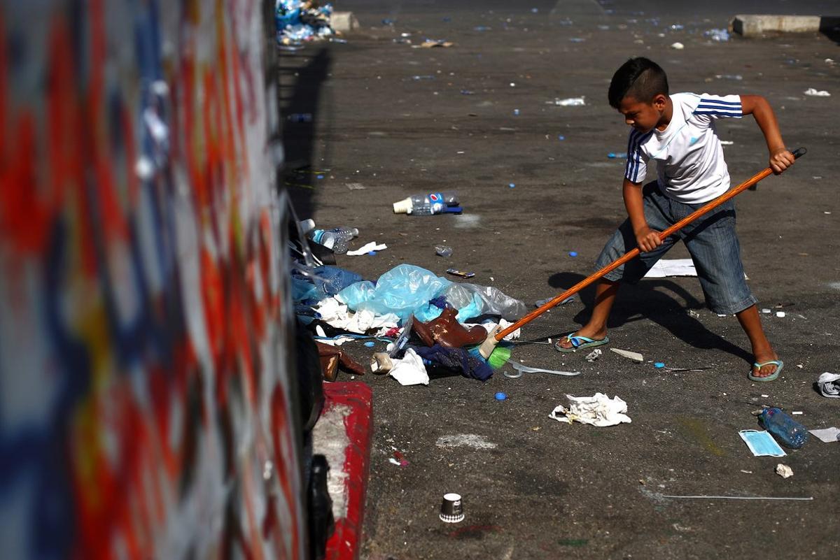 A boy sweeps rubbish at Martyrs’ Square after last night protests following Tuesday’s blast, in Beirut, Lebanon August 9, 2020. REUTERS/Hannah McKay