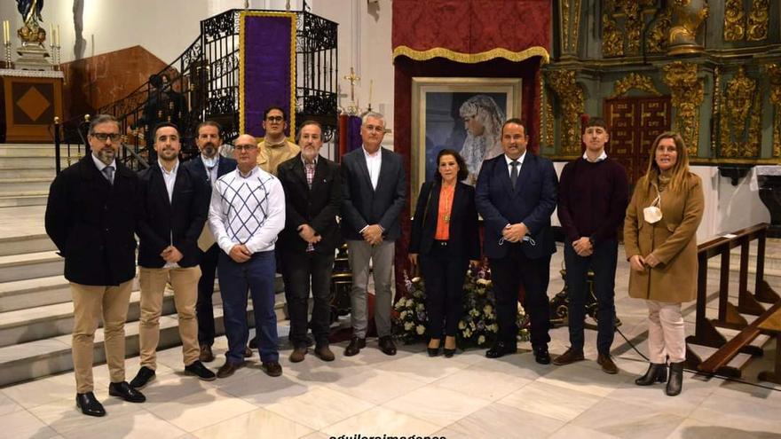 Representantes de la junta directiva de la Agrupación de Cofradías y del Ayuntamiento de Fernán Núñez, delante del cartel anunciador de la Semana Santa 2022, que es una imagen de María Santísima de la Paz y la Esperanza.