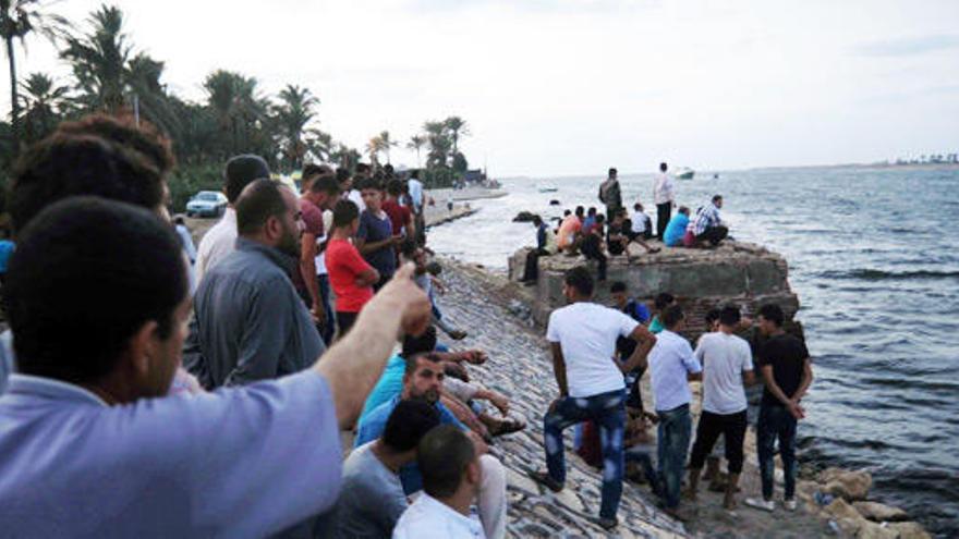 La gente se congrega en la costa donde ha naufragado el barco.