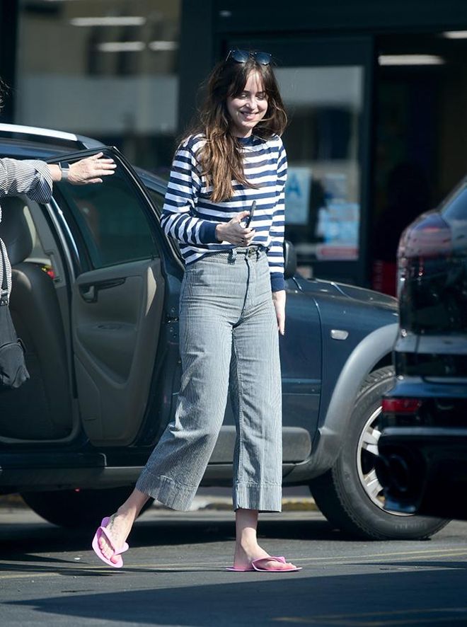 Dakota Johnson con chanclas, pantalones vaqueros y camiseta de rayas