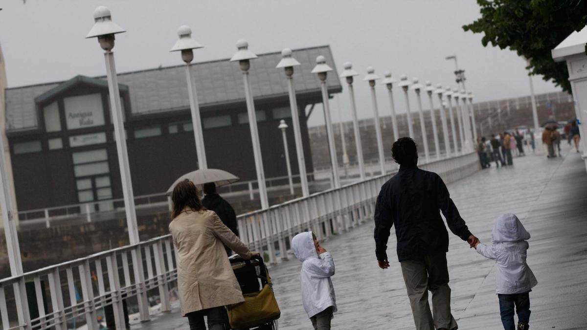 Turistas bajo el orbayu en Gijón en una imagen de archivo.
