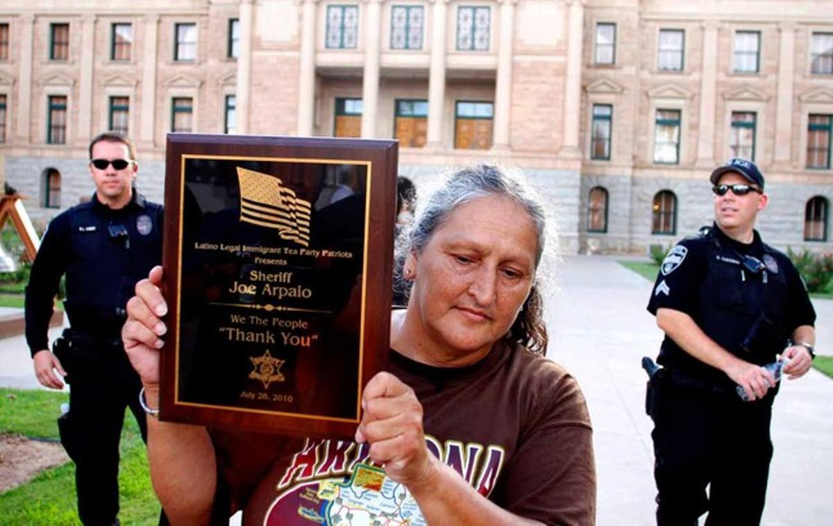 Una manifestante enseña la placa de agradecimiento que quiere regalar al ’sheriff’ Joe Arpaio.