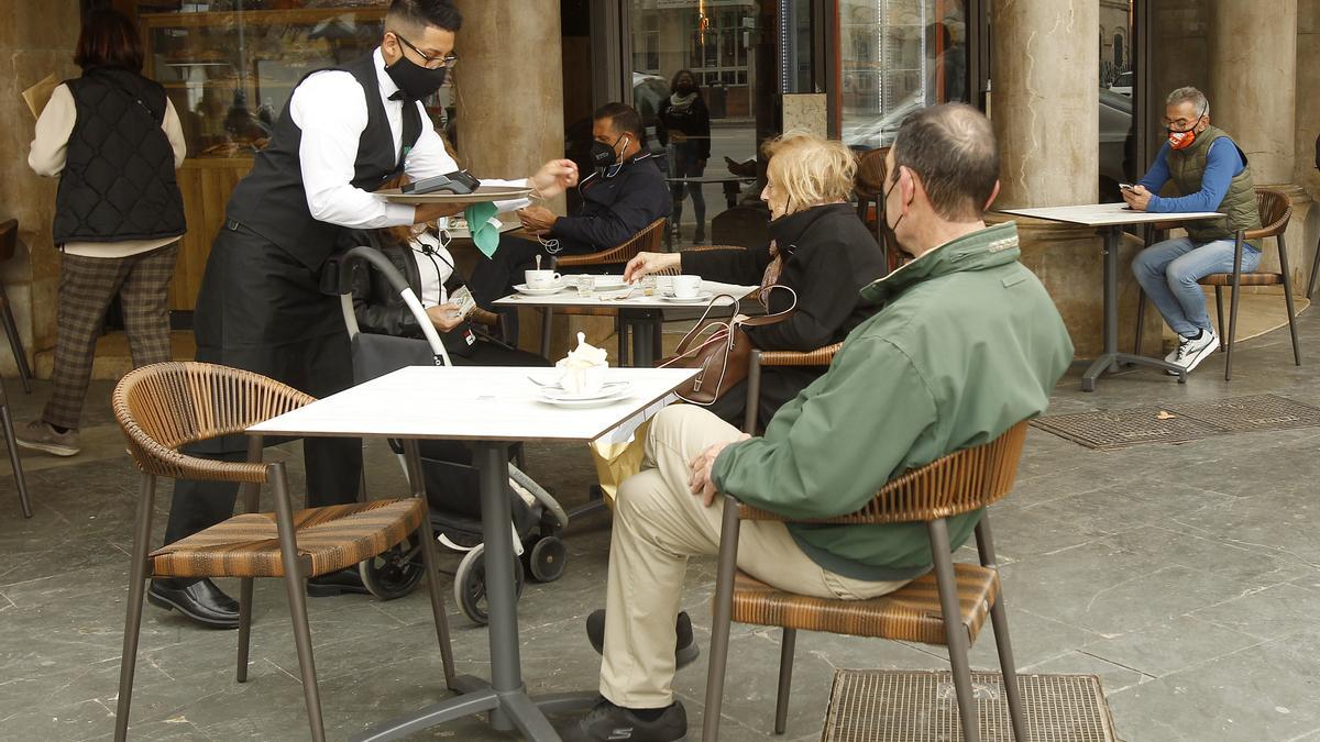 Un camarero atiende a varios clientes en la terraza de un bar en Palma.