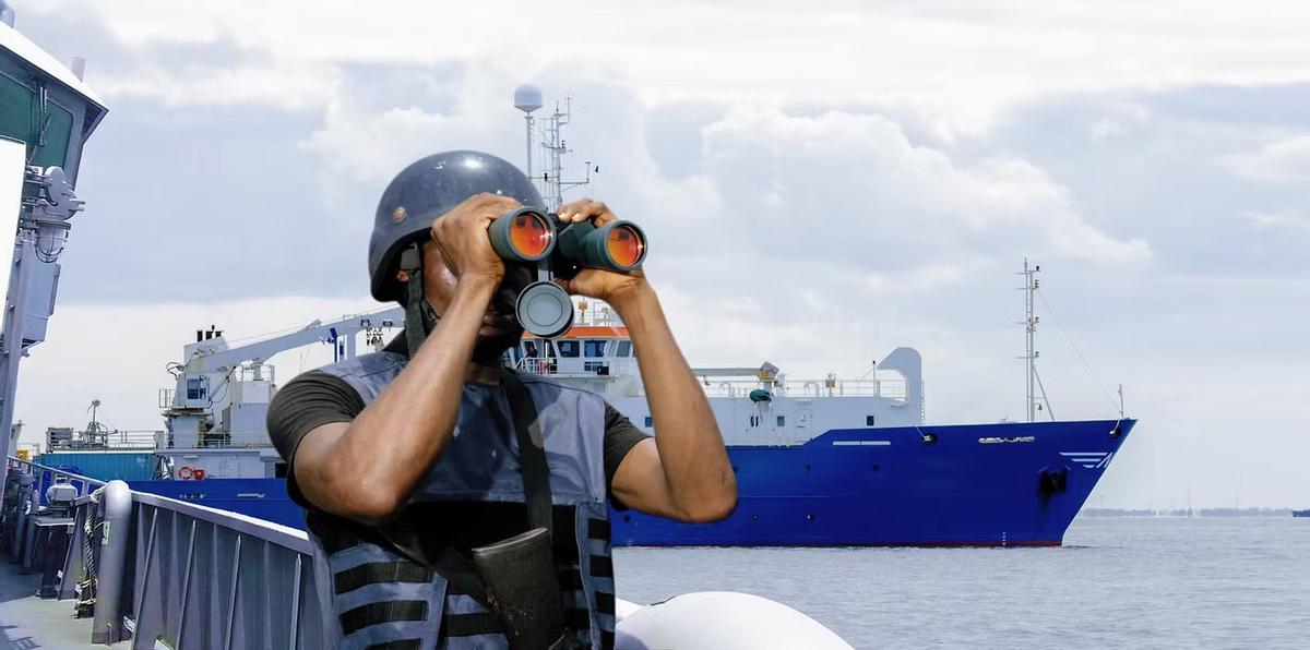 Personal de seguridad privada de un barco vigila a través de sus prismáticos el mar.