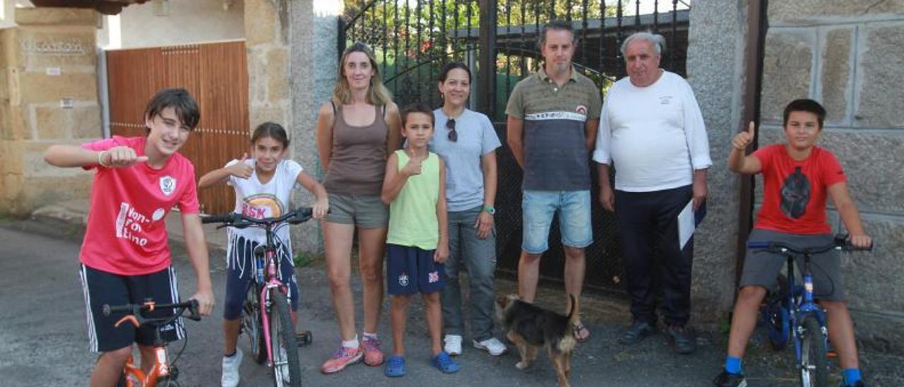 Jóvenes en bicicleta veraneando y dos de las nuevas familias en Vilameá, junto con Vicente, de la directiva de la asocicion del pueblo.   | // IÑAKI OSORIO