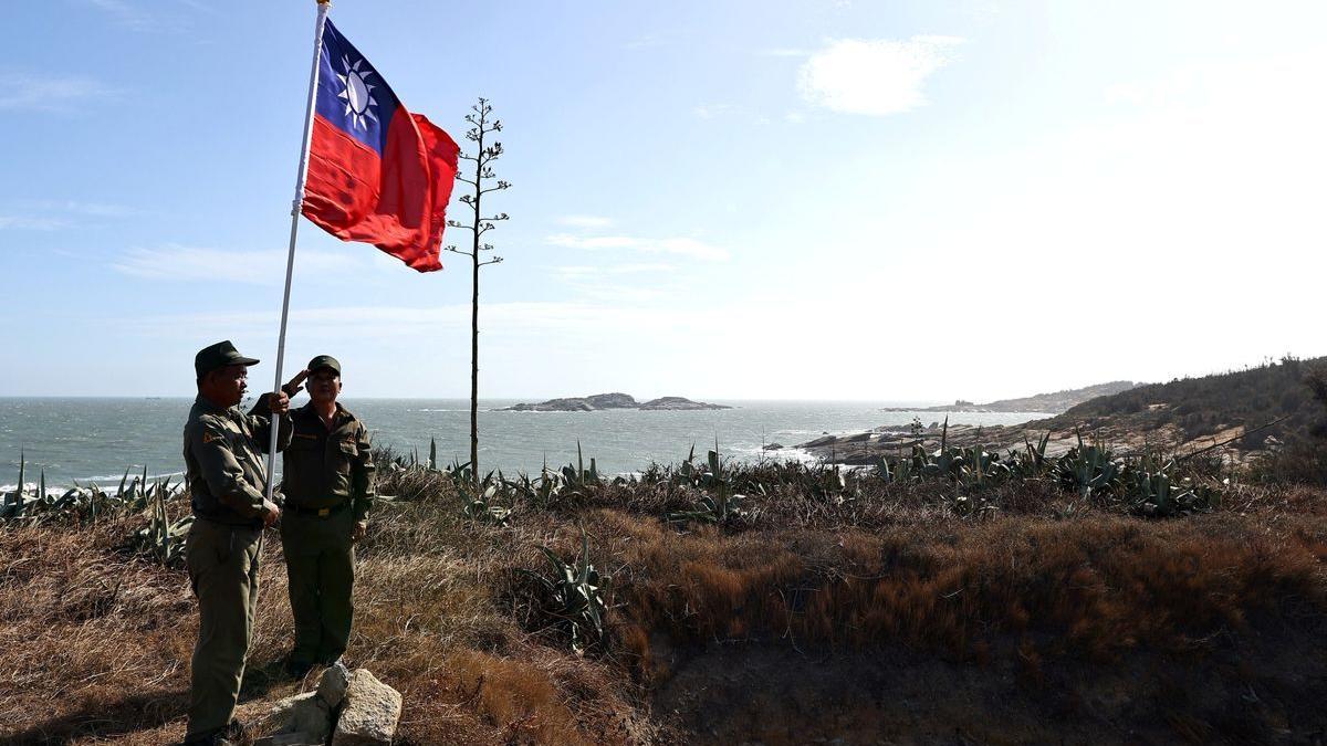 Dos veteranos del Ejército de Taiwán izan la bandera de Taiwán en el puesto miliar de Kinmen.