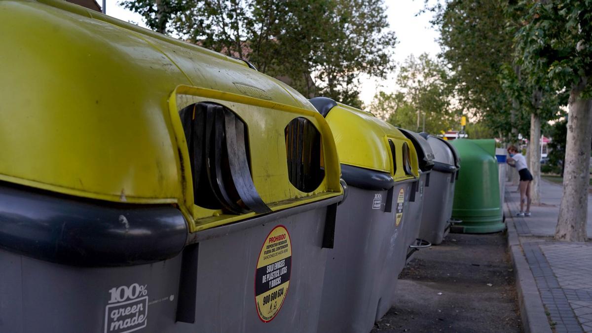 Una persona tira cartón al contenedor de reciclaje de papel y cartòn en Madrid.