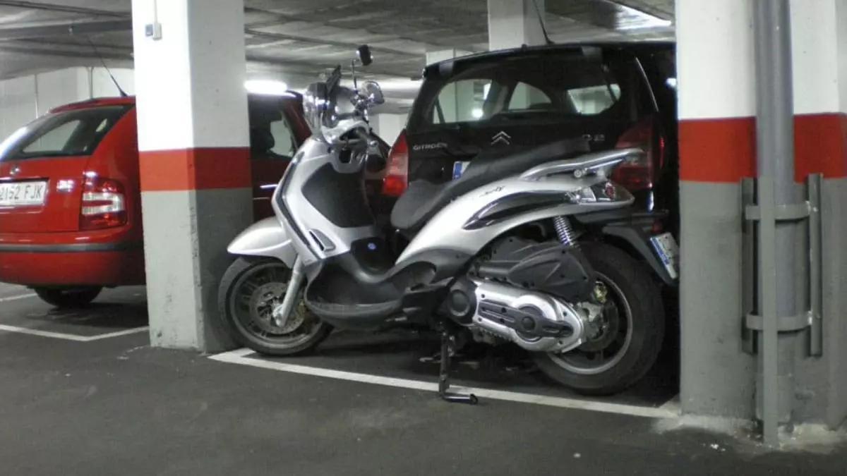Un coche y una moto comparten plaza de parquing en un garaje comunitario