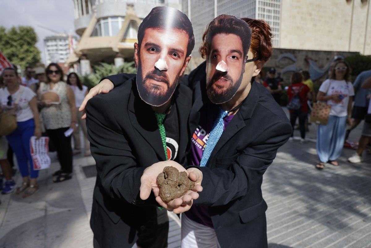 Dos manifestantes a las puertas de la Asamblea Regional con las caretas de los líderes regionales de Vox y del PP.