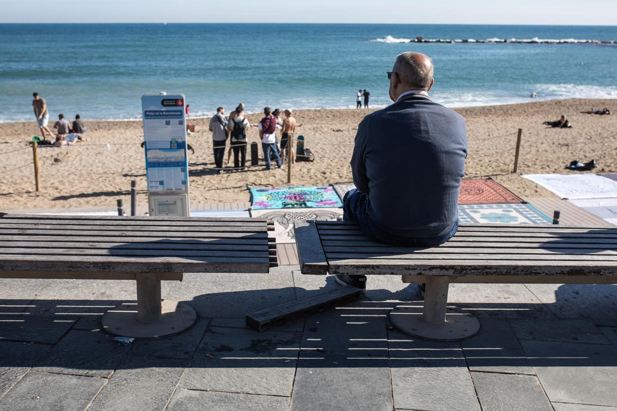 Un hombre sentado al lado de un banco con desperfectos.