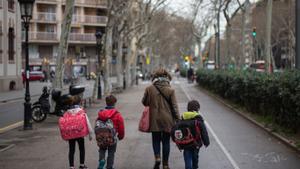 Imagen de archivo de una madre llevando a sus hijos al colegio