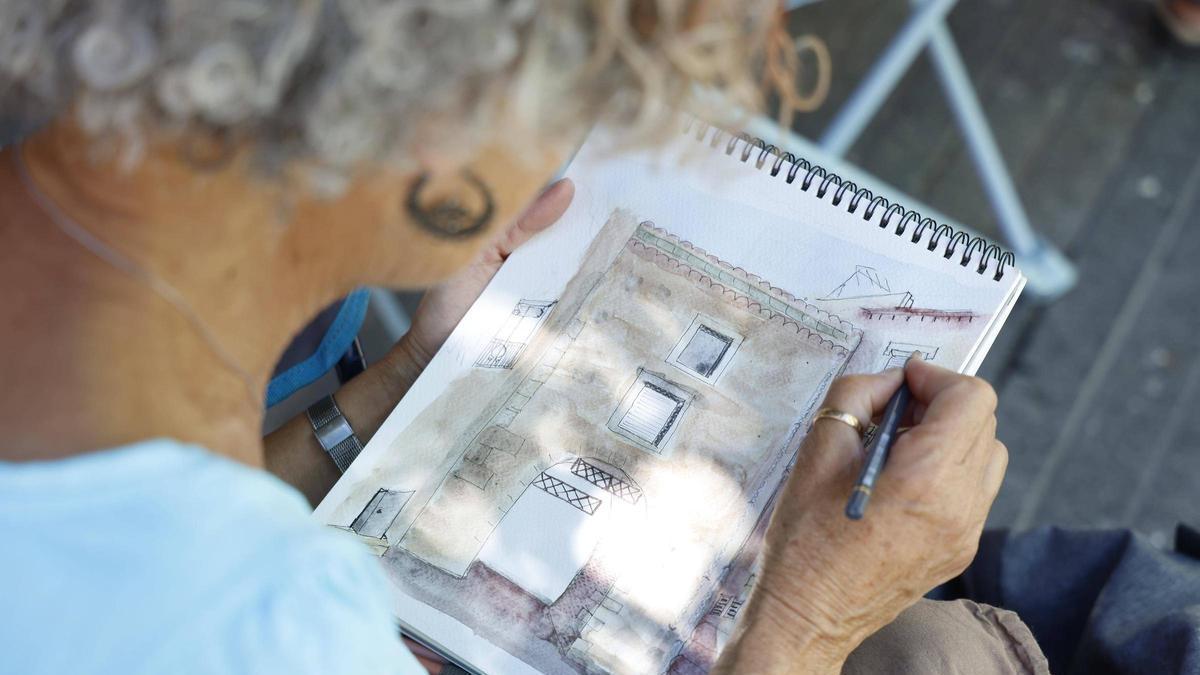 Una participant d’Urban Sketchers Girona dibuixa una façana de Peralada.