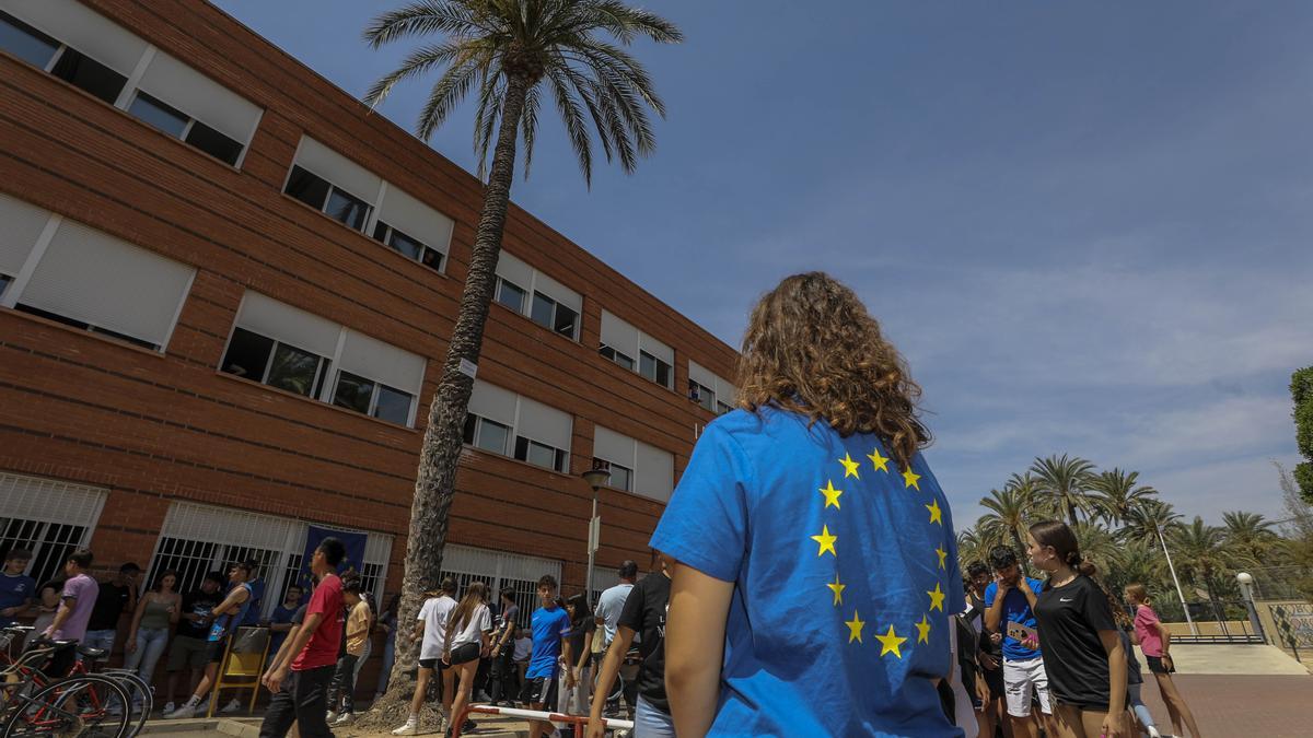 Alumnos con camisetas de la Unión Europea durante el acto miran la palmera en la que se ha colocado una placa conmemorativa.