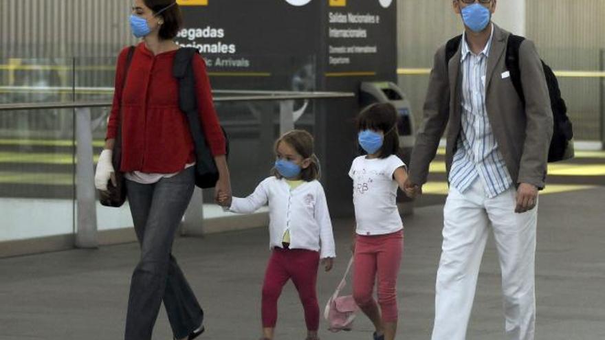 Una pareja y sus dos hijas, todos con mascarillas, en el exterior del aeropuerto de México DF
