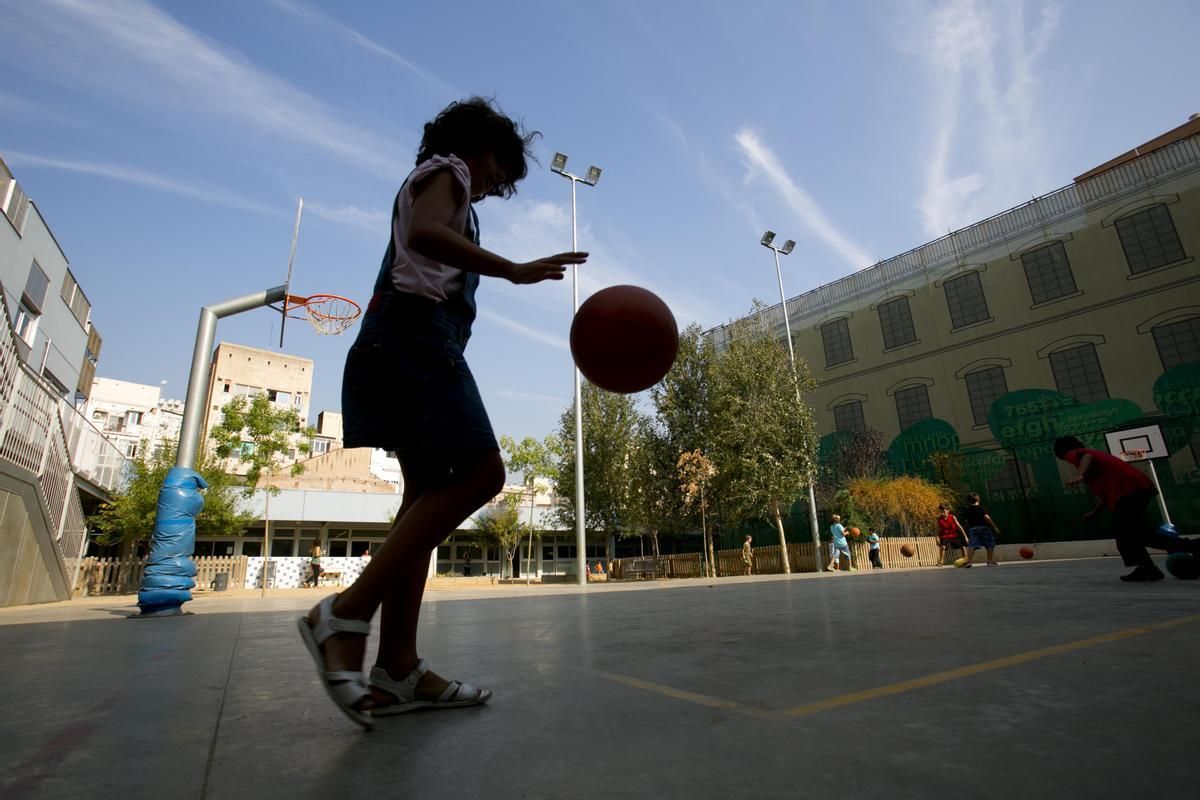 Una niña jugando a baloncesto en el patio del colegio.