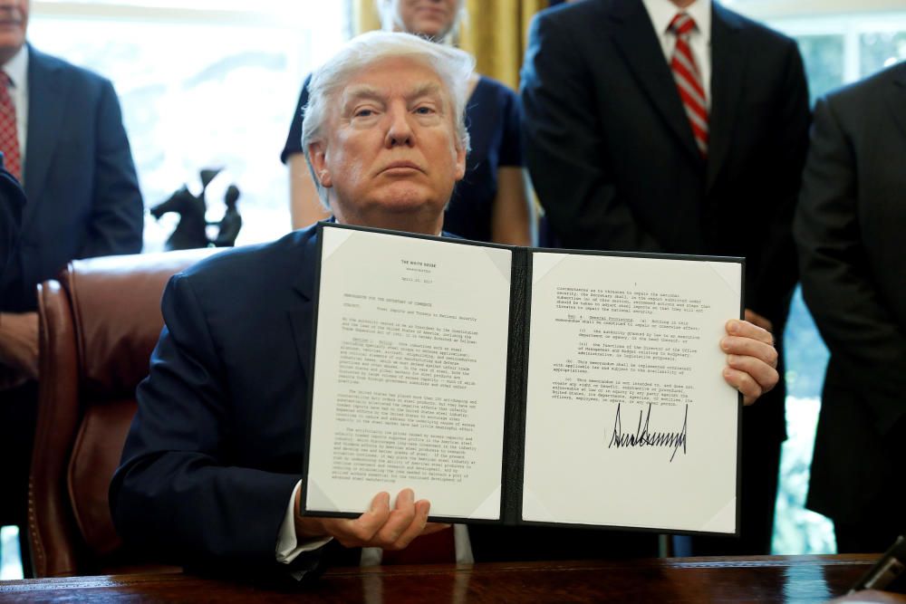 U.S. President Donald Trump holds up a directive ...