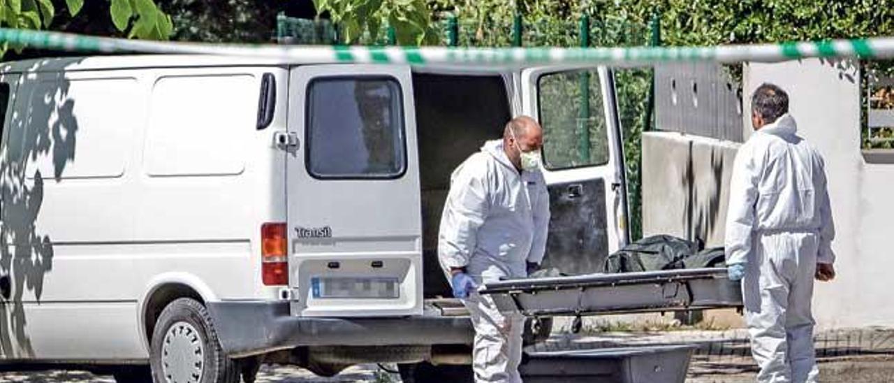 Operarios de los servicios funerarios introducen uno de los cadáveres en el furgón.