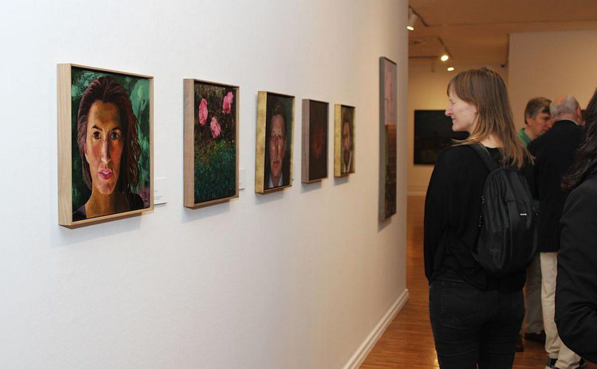 Una mujer contempla los cuadros de Reyes Díaz.
