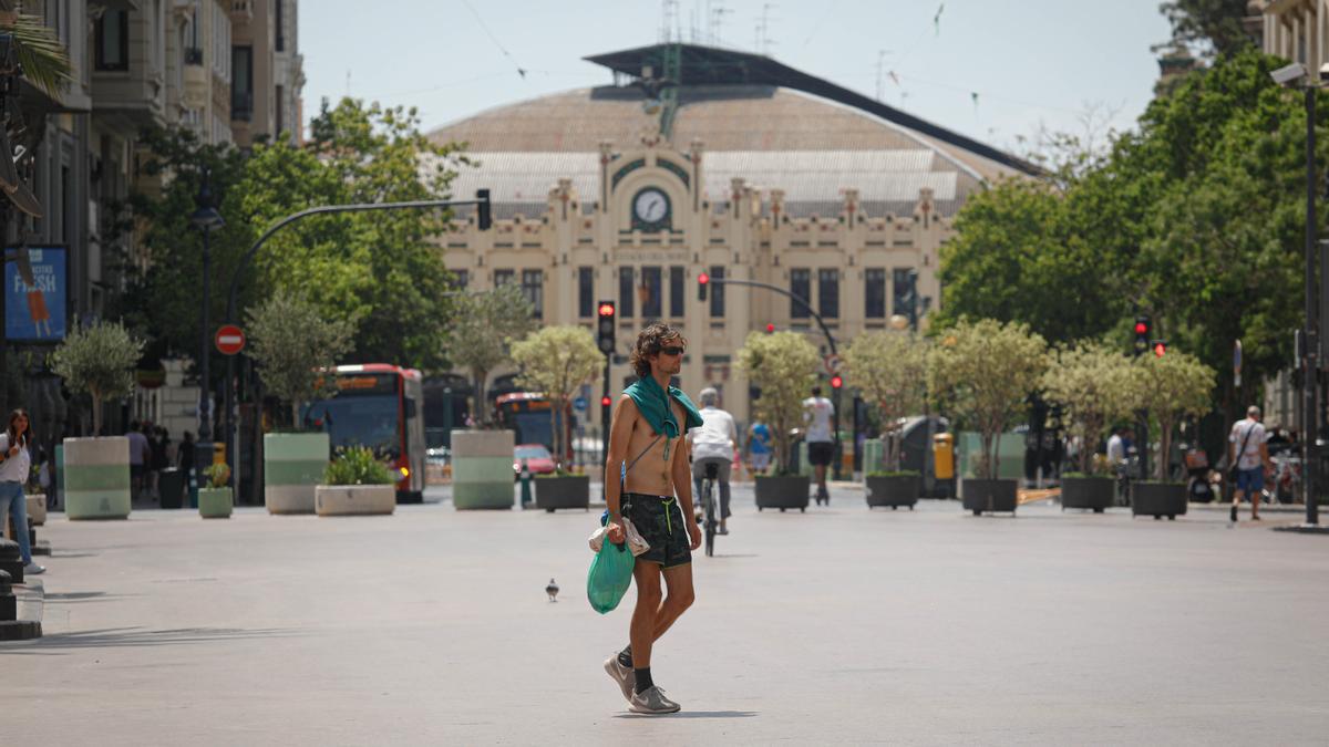 Un hombre pasea sin camiseta en plena ola de calor por el centro de València.