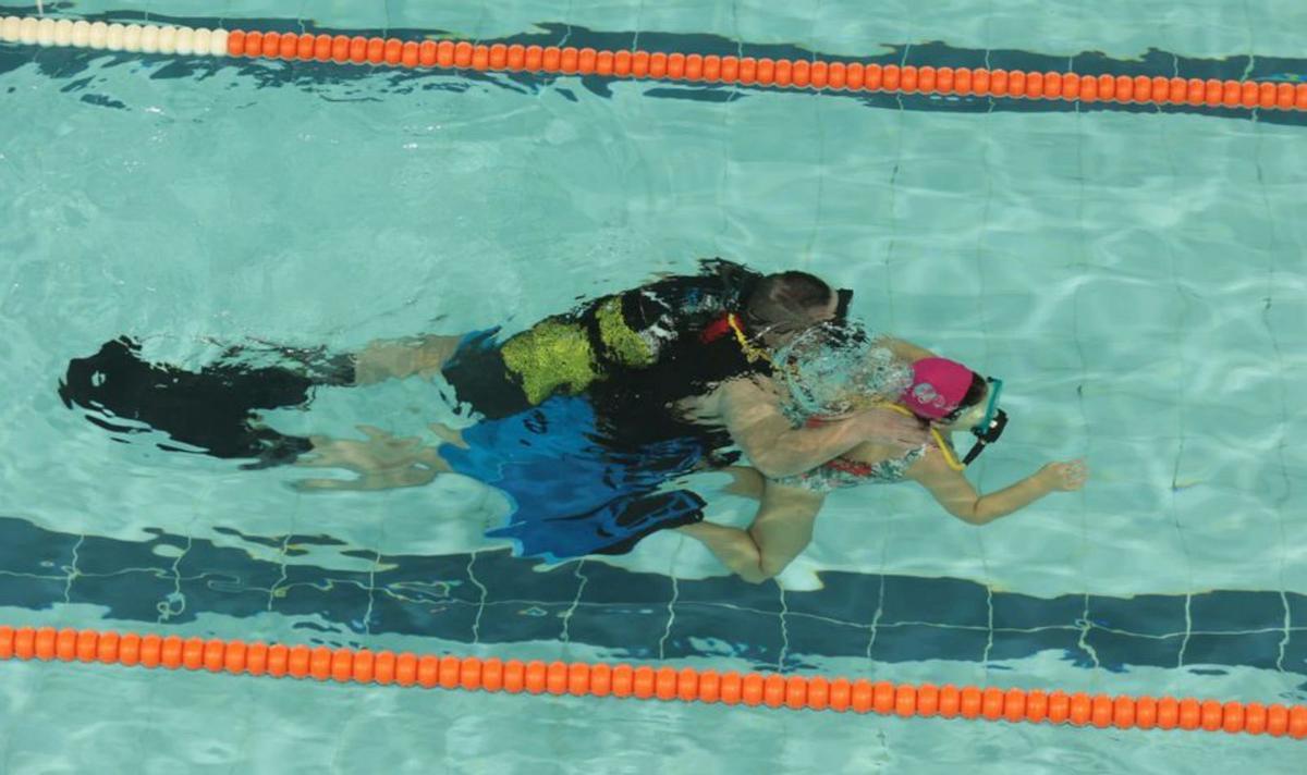 Arriba, los monitores del Club Buceo Ons dan instrucciones a los participantes. A la izquierda, una niña buceando.  | // JAVIER TENIENTE