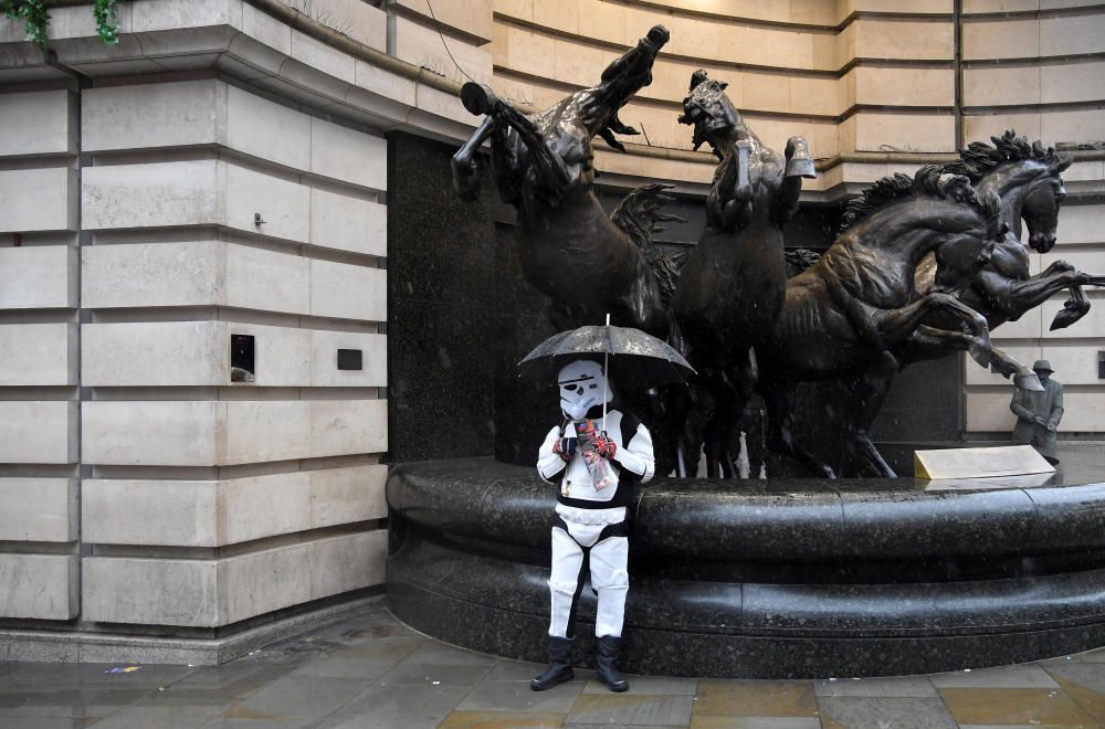 Un hombre vestido como un 'soldado imperial' de Star Wars se protege de la lluvia en Piccadilly Circus en Londres.