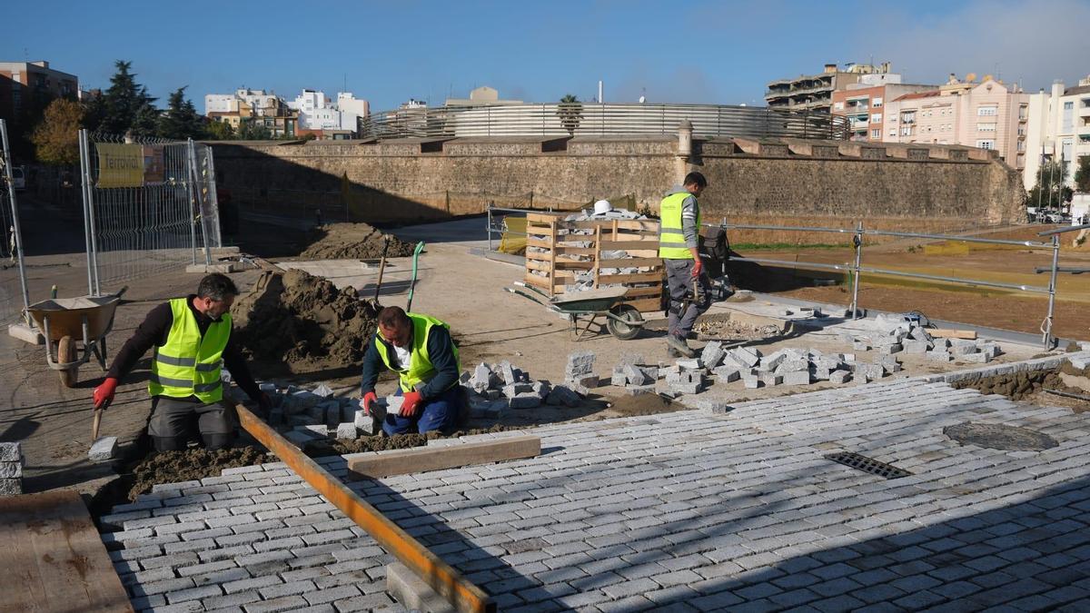 Los albañiles colocan los nuevos adoquines de granito en la calle Stadium.