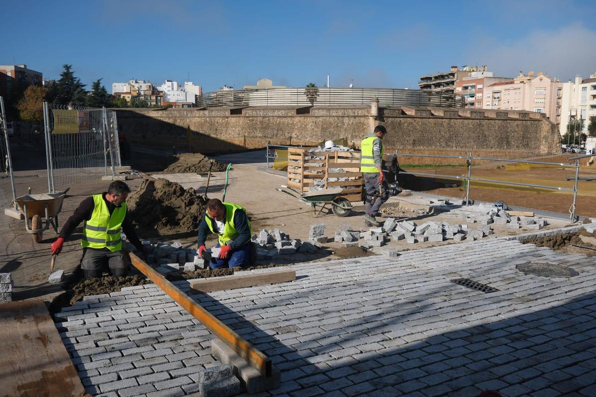 Los albañiles colocan los nuevos adoquines de granito en la calle Stadium.