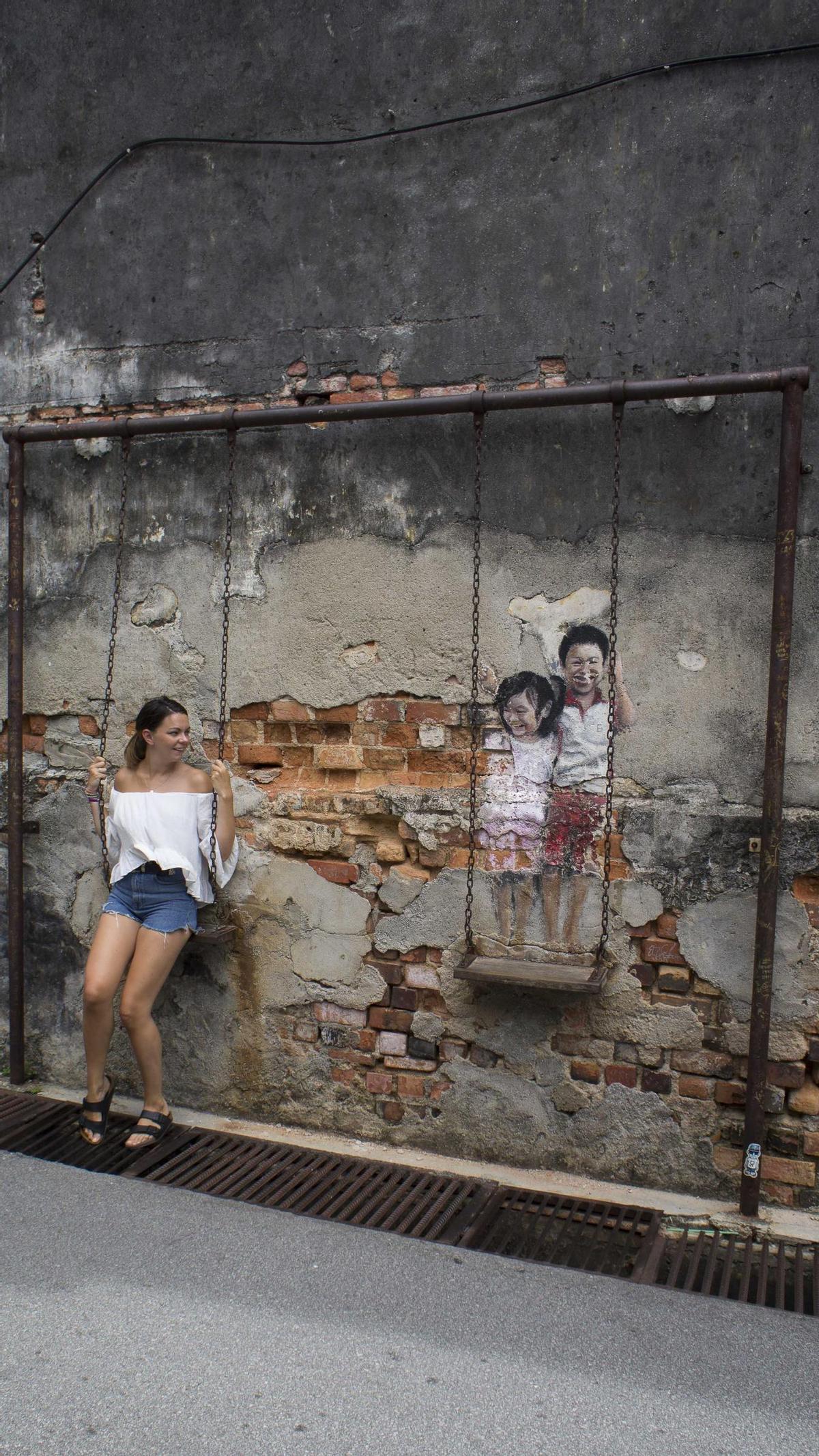 Una mujer se deja retratar junto a uno de los murales.