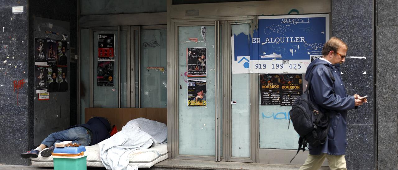Una persona duerme sobre unos colchones en la entrada de un local cerrado de Zaragoza.
