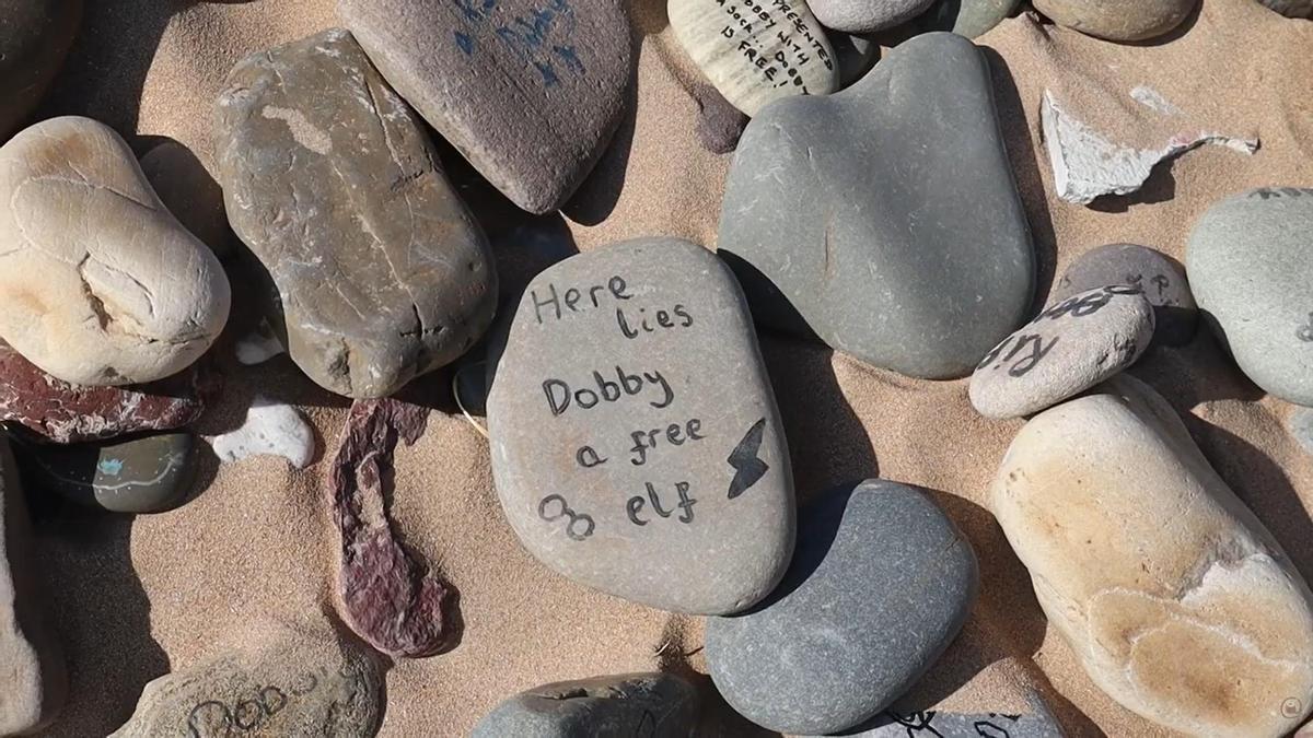 Captura de pantalla de una de las piedras que se encuentra en la tumba del elfo Dobby con la inscripción: "Aquí descansa Dobby, un elfo libre"