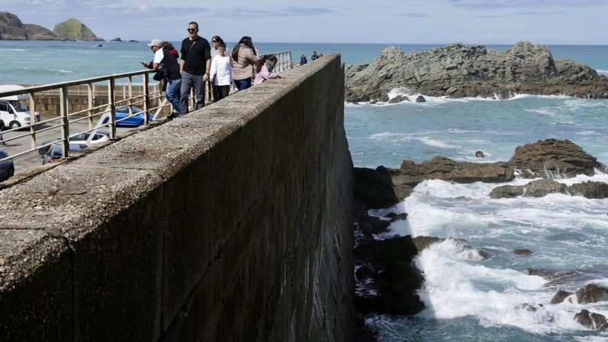 Viandantes paseando por el espigón de Cudillero el pasado sábado. | Juan Plaza