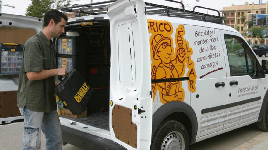 Un trabajador autónomo junto a su camioneta con material de bricolaje.