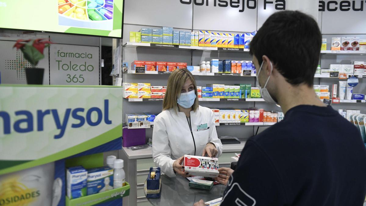 Una farmacéutica muestra a un usuario una caja de mascarillas en Murcia