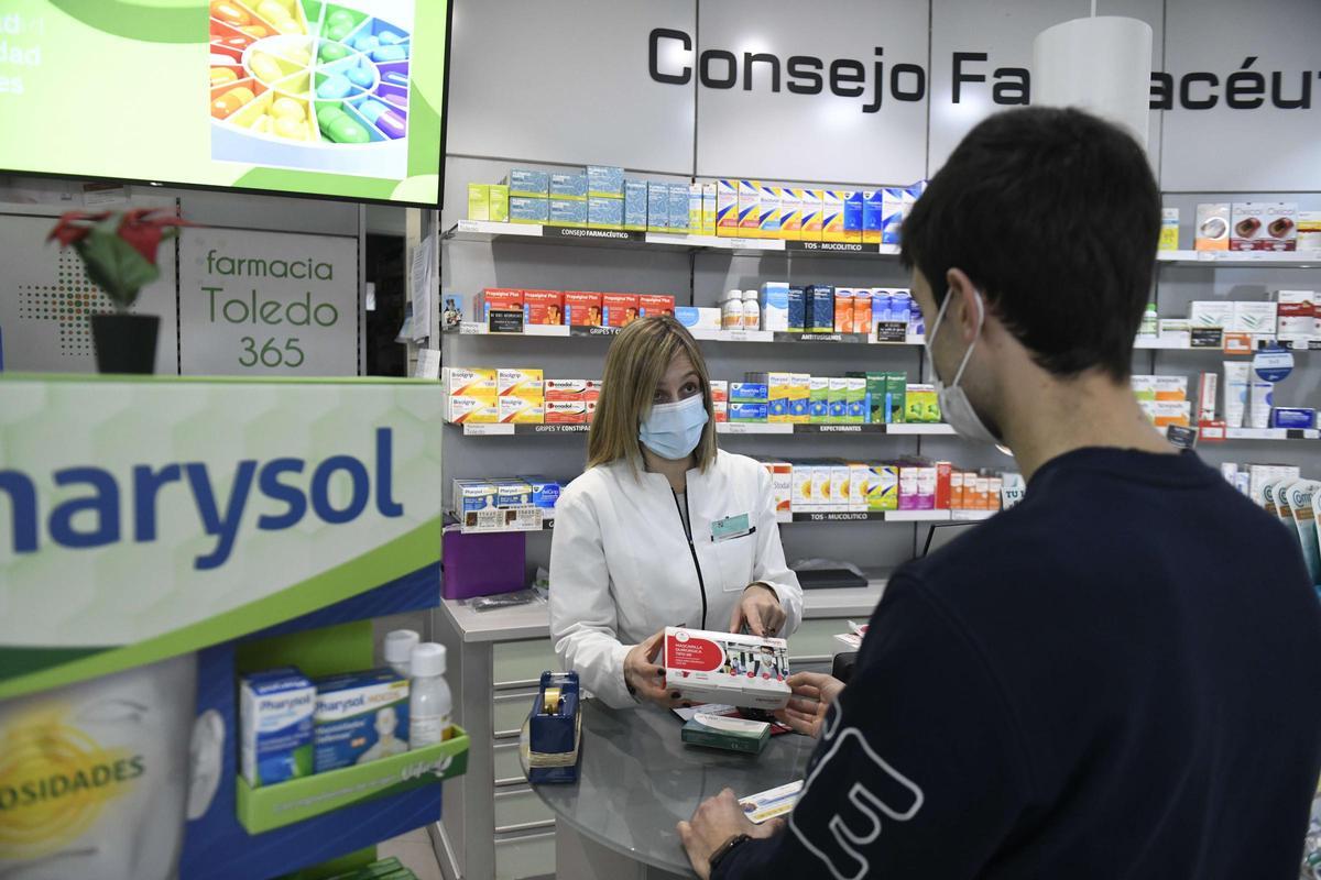 Una farmacéutica muestra a un usuario una caja de mascarillas en Murcia