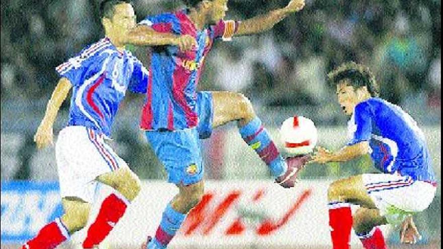Ronaldinho intenta controlar el balón ante la oposición de dos jugadores japoneses.