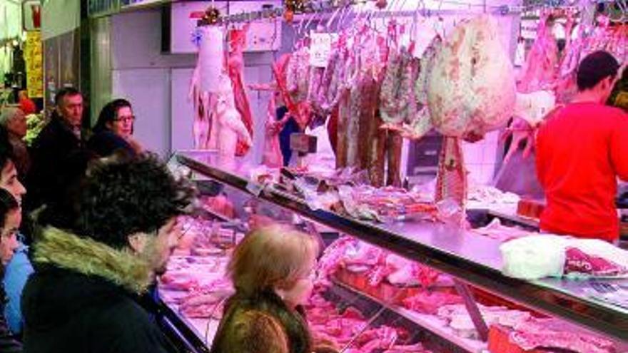 Varios clientes compran carne en un puesto del Mercado de Abastos.