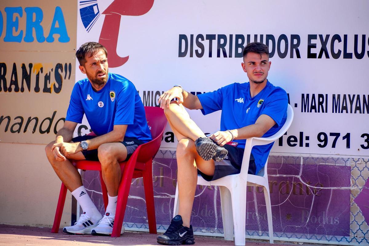 Míchel, sentado en una silla fuera del banquillo, junto a Diego Lorenzo, ambos fuera de la convocatoria en Formentera pese a viajar.