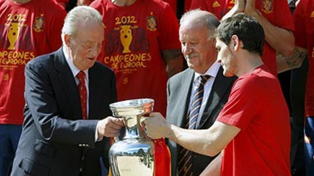 El rey Juan Carlos recibe de manos del capitán de la selección española de fútbol, Iker Casillas.