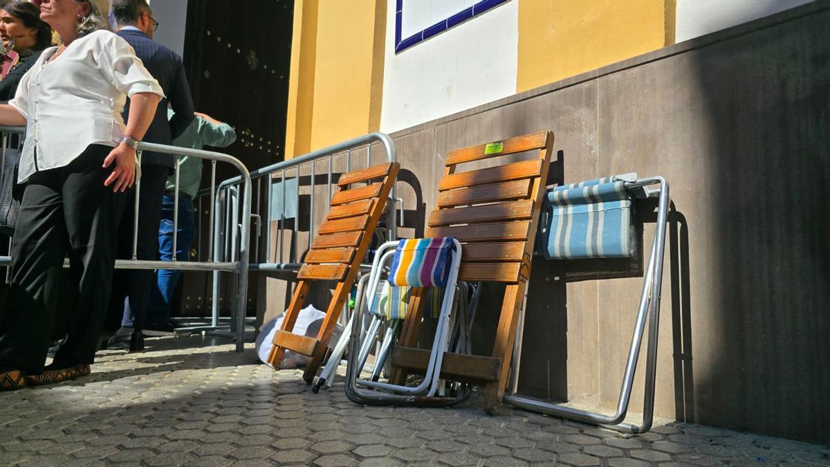 Sillitas portátiles apoyadas en la pared en la tarde del Jueves Santo en la calle Pureza.