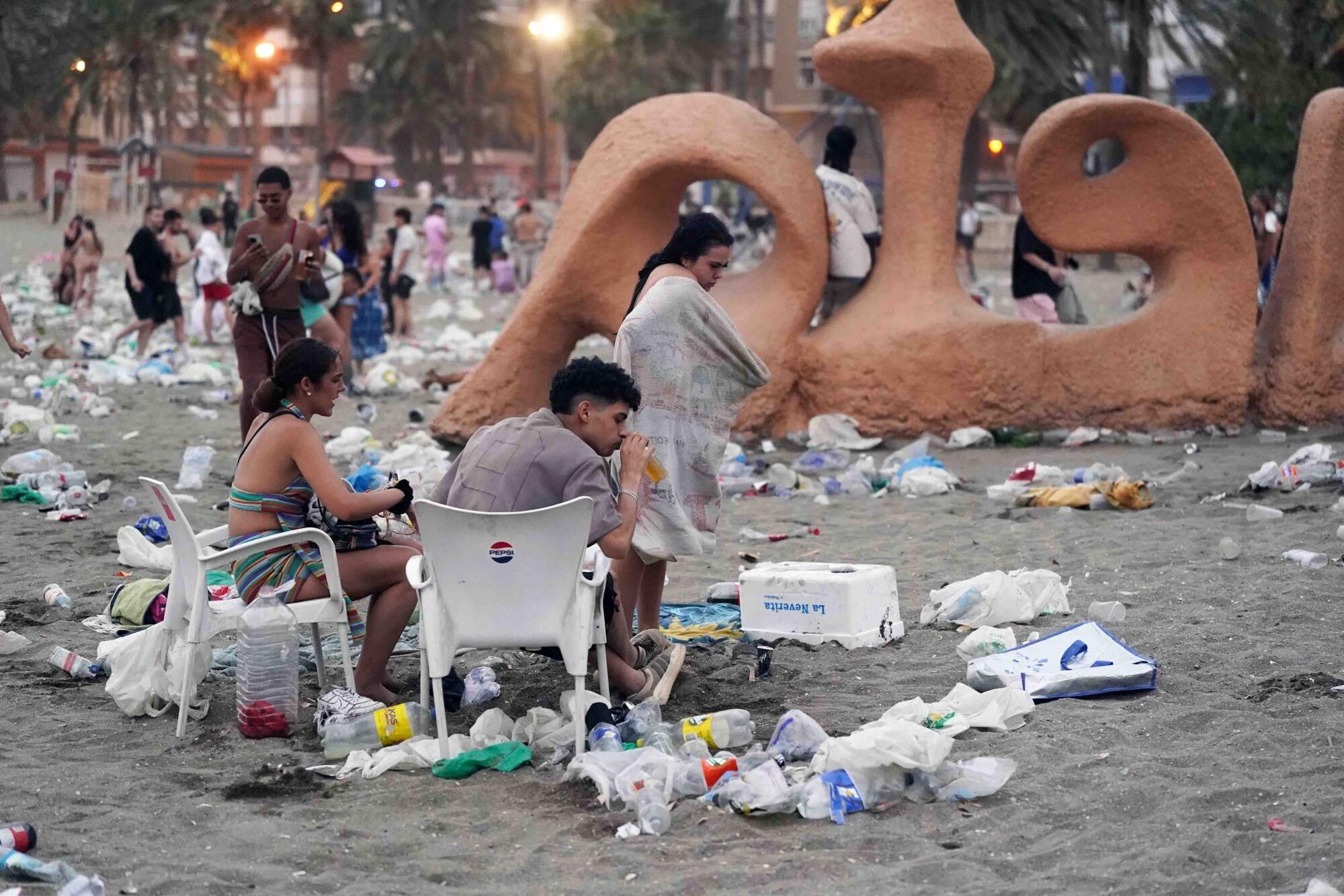 Varios operarios de la empresa de limpieza de Limasam, recogen los residuos de la playa de La Malagueta, tras la Noche de San Juan en Málaga 2025