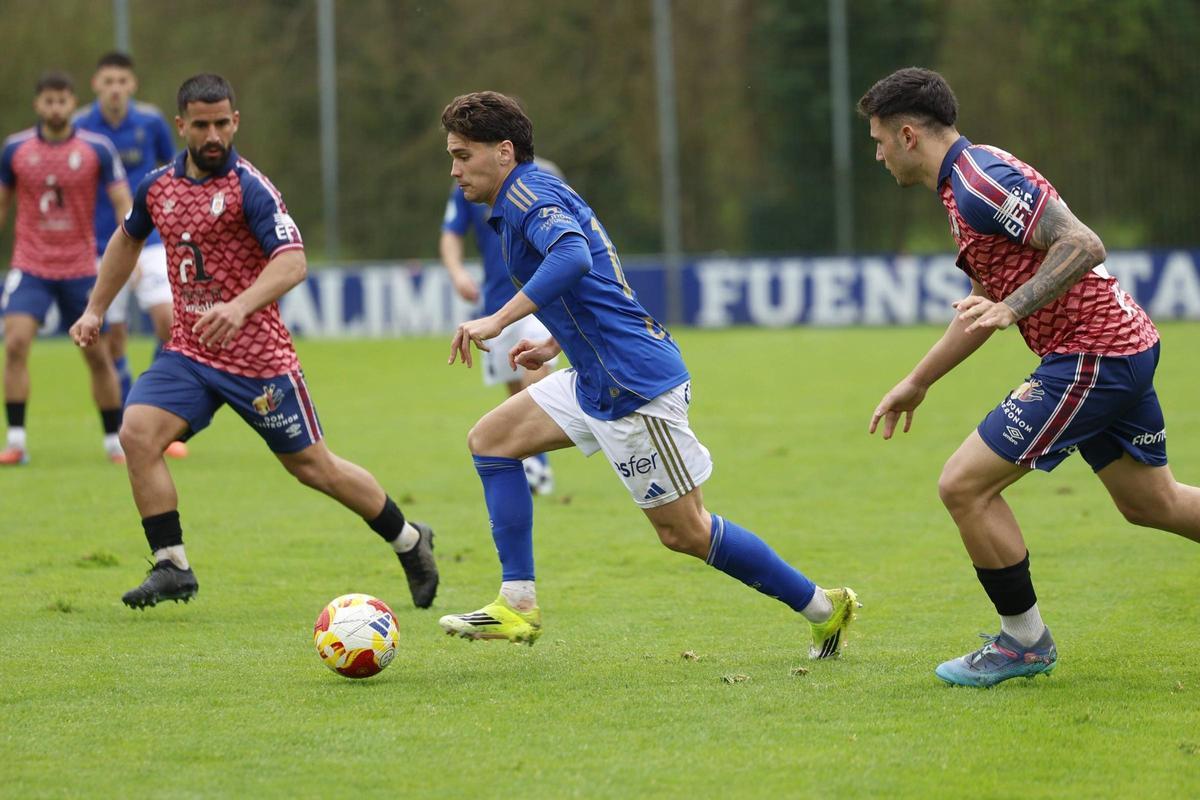 Pablo Agudín conduce el balón ante la mirada de dos futbolistas del Ávila, ayer, en El Requexón.