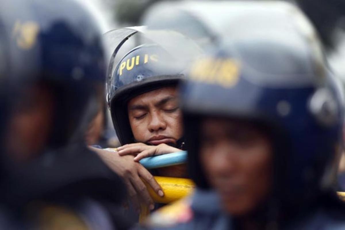 Un policia antiavalots fa una migdiada mentre milers de manifestants filipins protesten contra el president filipí Benigno Aquino III.