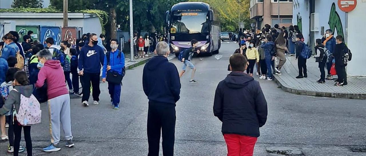 Un autobús accede a la zona escolar de Santa Mariña con la calle llena de niños y padres. |   // FDV