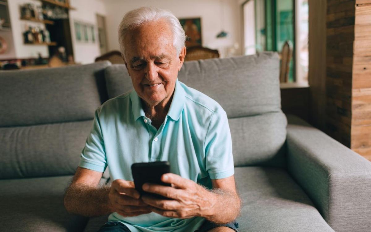 Jubilado revisa la cuenta bancaria en su teléfono móvil.