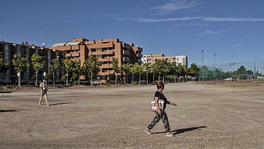 Varias personas pasan por el solar afectado, ayer por la tarde.