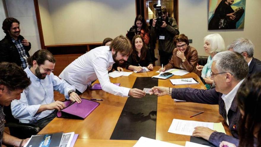 Manuel Orviz (a la derecha) da su tarjeta a Daniel Ripa, en una reunión entre Podemos e IU en la Junta.