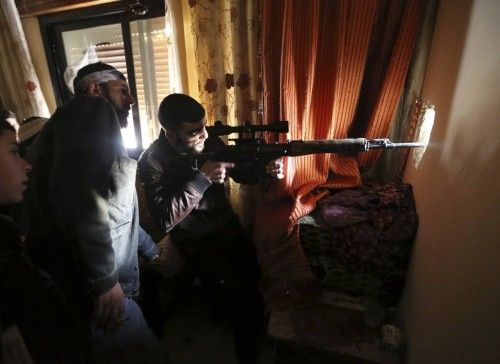 A Free Syrian Army fighter fires a sniper rifle at Syrian Army check point in Haresta neighbourhood of Damascus
