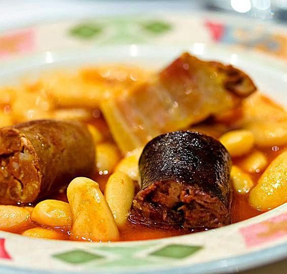 Un plato de fabada y una cucharada de fabers con compango. | Foto Turismo Asturias/ Les Fartures/ Noé Baranda