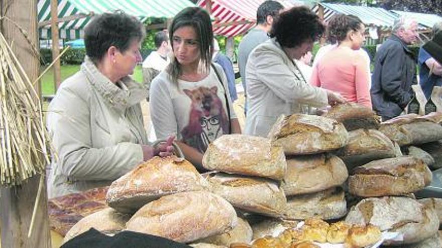 Uno de los puestos de pan de escanda instalados ayer en el mercado moscón. A la derecha, la demostración de «mayar a manal».